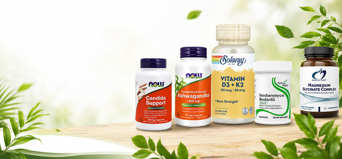 Assorted dietary supplement bottles on a wooden surface with green leaves and a bright, natural background.