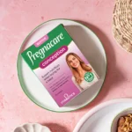 Box of Pregnacare Conception prenatal vitamins on a white plate atop a pink surface.