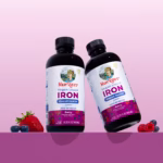 Two MaryRuth's Vegan Liquid Iron bottles tilted, with berry-flavored labels, against a pink gradient background and berries at the bottom left and right.